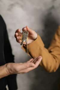 business succession planning One person passing keys to another person, representing business succession.