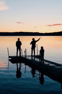 family governance meetings Family of three fishing on a pier at a mountain lake.