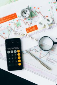investment management Candlestick charts, phone, and magnifying glass for stock research.