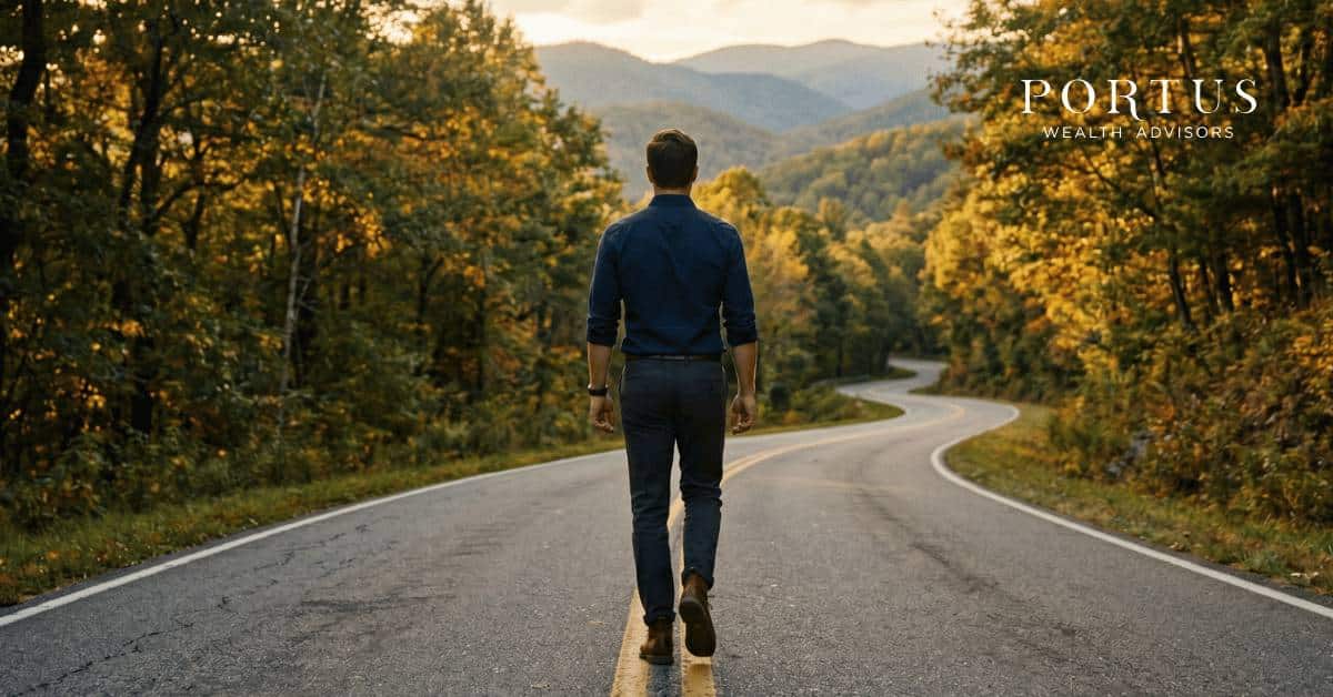 A lone male figure in smart business casual clothing -- dark trousers, a well-fitted button-down shirt, no jacket -- walking away from the camera down a winding two-lane mountain road. The figure is centered in the frame, mid-stride, posture confident and purposeful, not hurried. His back is fully turned to the camera so his face is never visible. The road curves gently ahead of him and disappears into a canopy of mature hardwood trees -- oaks, maples, and birches -- with late afternoon golden light filtering through the leaves and casting long, warm shadows across the asphalt. The surrounding landscape is unmistakably Blue Ridge -- rolling green hills layered in the background, a soft haze in the distant valleys, the kind of scene familiar to anyone who has driven through western North Carolina. The light is rich and warm, the golden hour just before sunset, with the brightest glow coming from the direction the figure is walking toward. The road ahead looks open, clear, and worth walking toward. The overall mood is cinematic, calm, and forward-moving -- a sense of quiet purpose and earned confidence rather than urgency or drama. No cars, no signs, no other figures. Just the man, the road, and what lies ahead. Shot as if from a professional cinema camera at ground level, slightly wide angle, with the road and figure as the central compositional element. Portus Wealth Advisors logo in the top right corner.