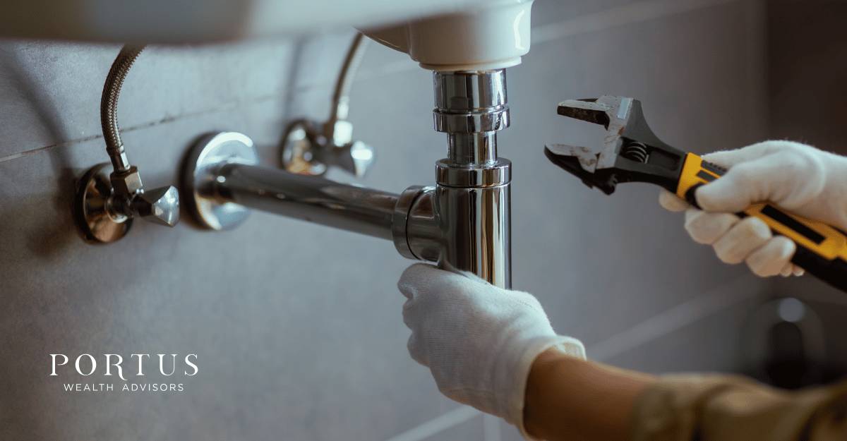 A bathroom sink with a pair of gloved hands from a plumber attaching pipes for the "selling my Charlotte NC trades business" blog post. Portus Wealth Advisors logo in the bottom left corner.