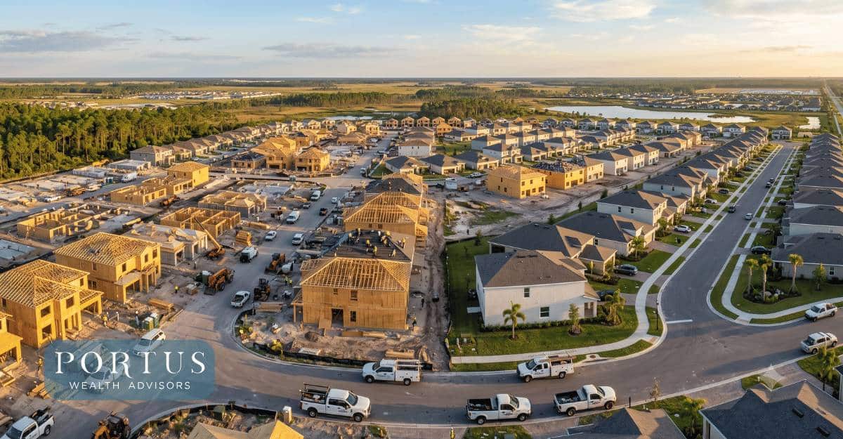 a wide aerial of an active Florida residential development under construction -- dozens of homes in various stages of completion, framing, roofing, and finishing visible from above, shot at golden hour with Florida's flat landscape and blue sky in the background for the "Exit Planning for Florida Trades Owners: Roofing, HVAC & More" blog post. Portus Wealth Advisors logo in the bottom left corner.